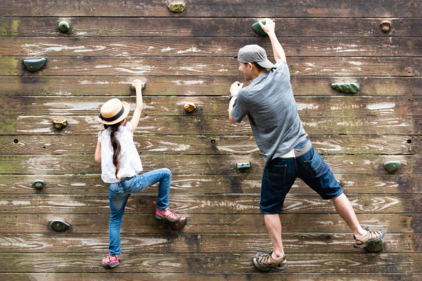padre e figlia che si arrampicano su un muro - park child asia lifestyles foto e immagini stock