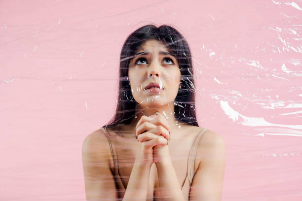 istock Beautiful young woman behind plastic wall tearing it up with her hands 1161760613