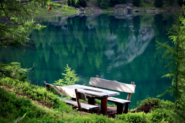 istock resting place/wooden bench at a mountain lake 1161764579