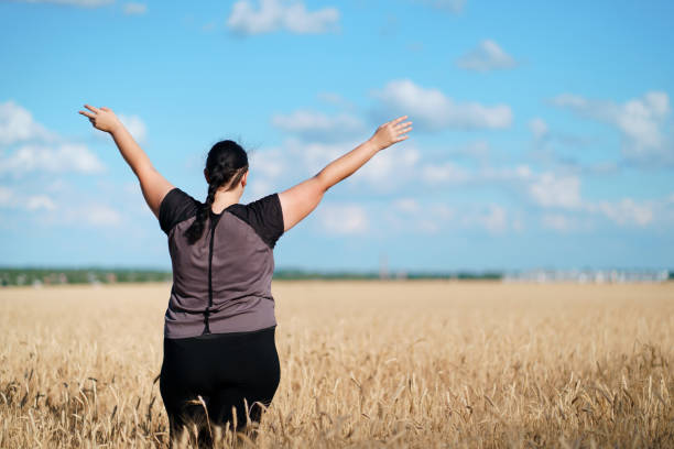 istock Overweight woman rising hands towards the sky 1161768949