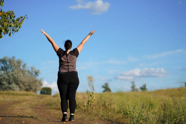 istock Overweight woman rising hands towards the sky 1161768962