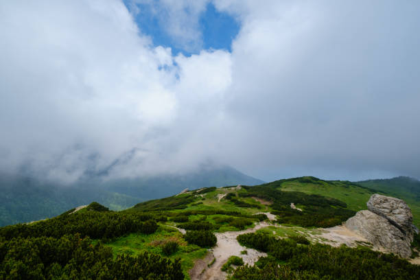 Summer mountain ridge with big stony rocks. And clouds and fog. Carpathian, Chornohora, Vuhatyj Kaminj, Ukraine.