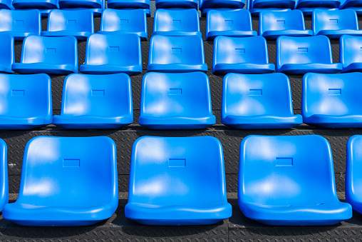 Blue seats on the grandstand of the football stadium.