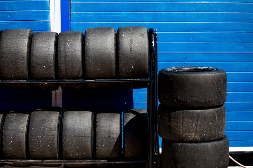 Image of racing tires piled up with a blue background