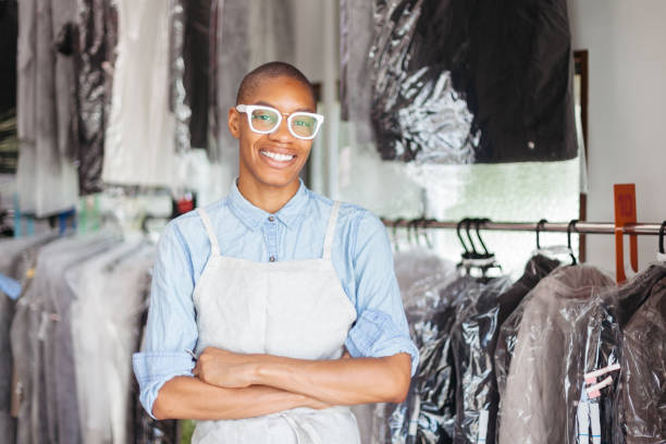 Portrait of young woman at dry cleaning shop A portrait of a young black woman with a smile at dry a cleaning shop dry cleaner stock pictures, royalty-free photos & images