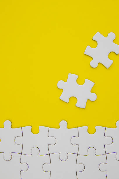 istock White jigsaw puzzle pieces on yellow background with negative space 1161780372