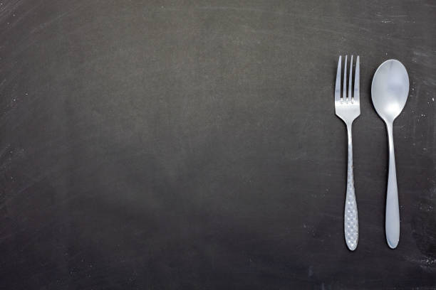istock Stainless steel spoon and fork on black wood or chalkboard background 1161781277