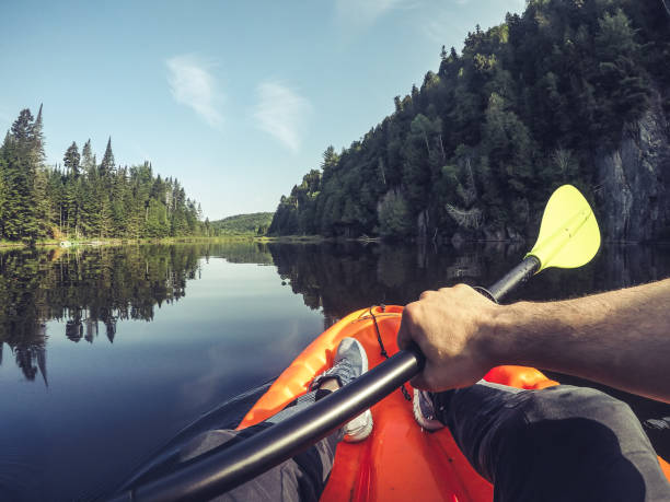 Man kayaking in morning on a small lake in the laurentian mountains in Quebec