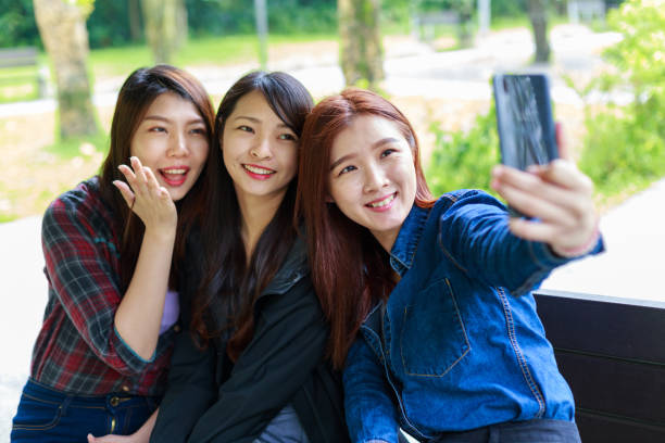istock 3 Asian girls taking selfie in a park 1161786322