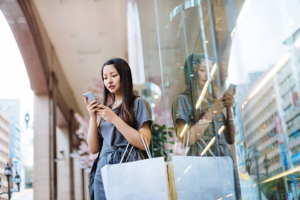 istock Asian girl with a shopping bag using smart phone 1161786373