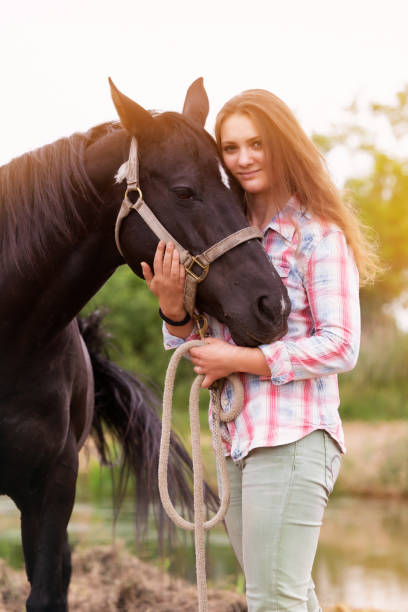 istock brunette young woman standing outdoors with her black horse 1161786720