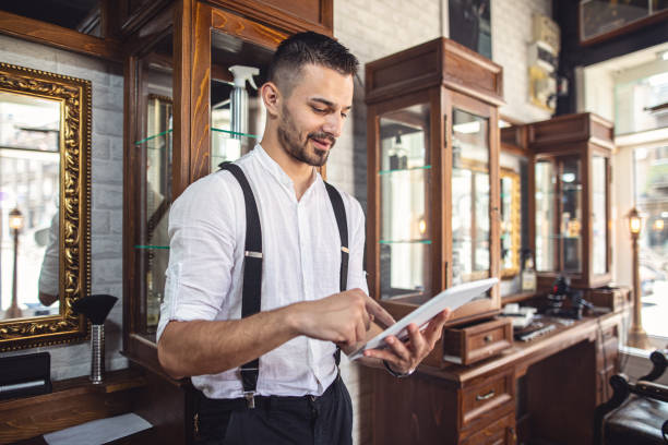 istock Old fashioned barber using a digital tablet in his shop 1161789097