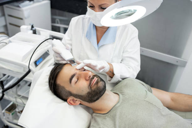 Young Man in Beauty Clinic Receiving Ultrasound Facial Cleaning Procedure stock photo