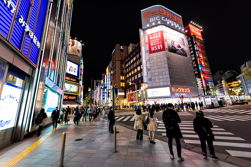 Shinjuku, Japan - April 4, 2019: Street outside view on Bic Camera electronics store shop at M Square with people crossing scramble crosswalk at night in Tokyo