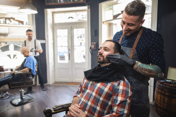 istock Smiling barber massaging customer's beard before shaving 1161791679