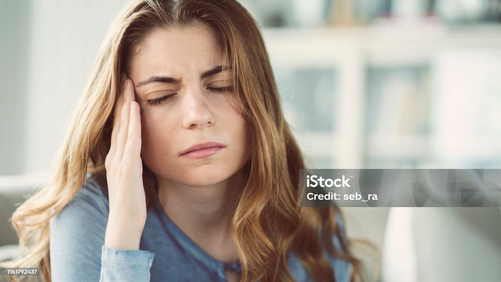 Young woman with headache in home interior Headache Stock Photo