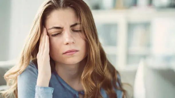 Photo of Young woman with headache in home interior