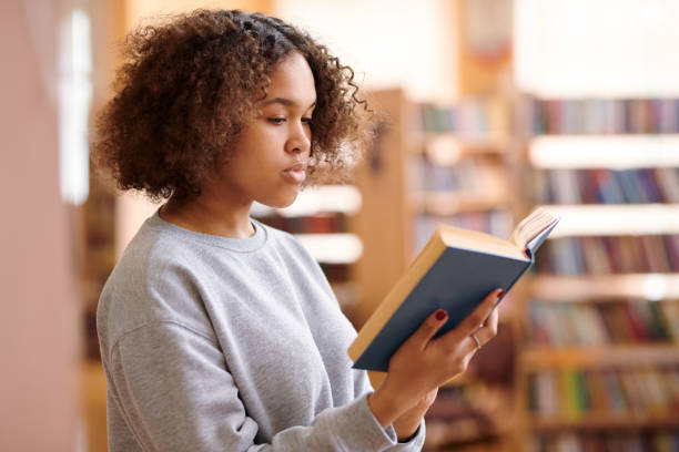 istock Pretty college student in casualwear reading interesting book 1161792597
