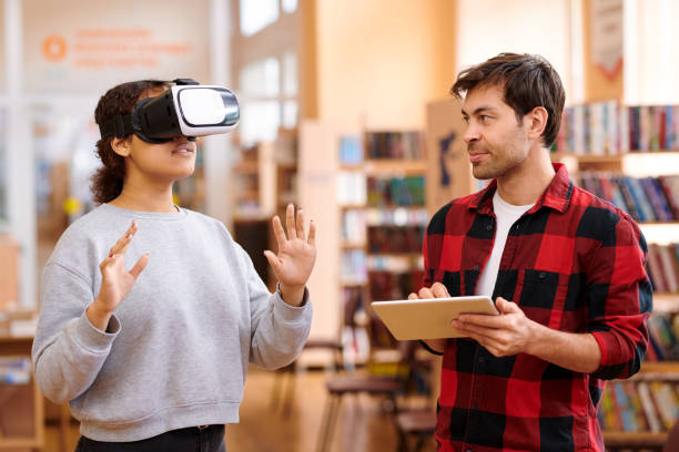 istock Young man with tablet interacting with his classmate in vr headset 1161792618