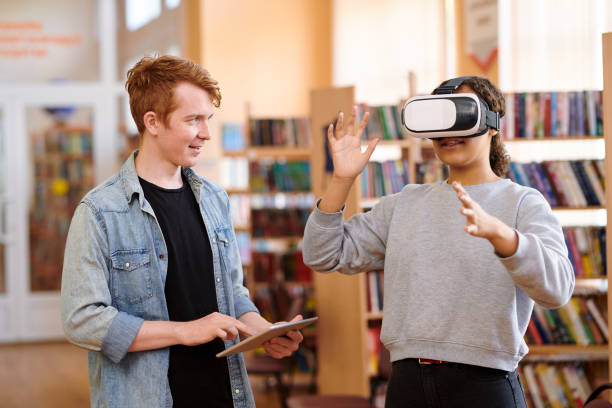 istock Mixed-race student with vr headset and her classmate with touchpad 1161792686