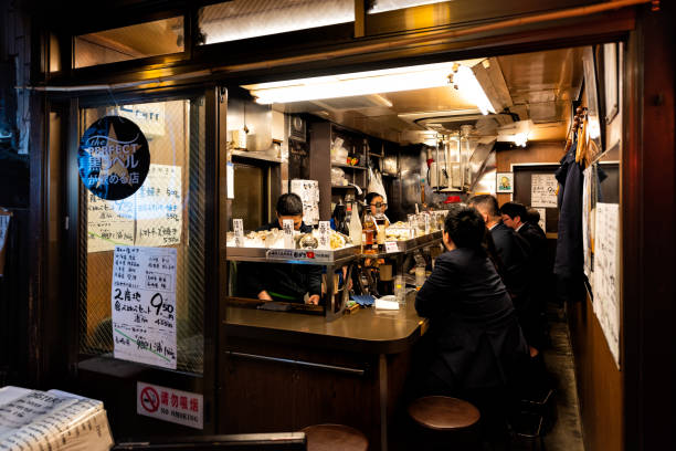 memory lane alley with izakaya pub, people sitting and eating by sidewalk in tokyo city at night, chef cooking food - business styles foods and drinks drinking imagens e fotografias de stock
