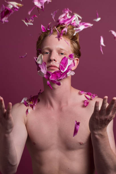 Young redhead man throwing flower petals