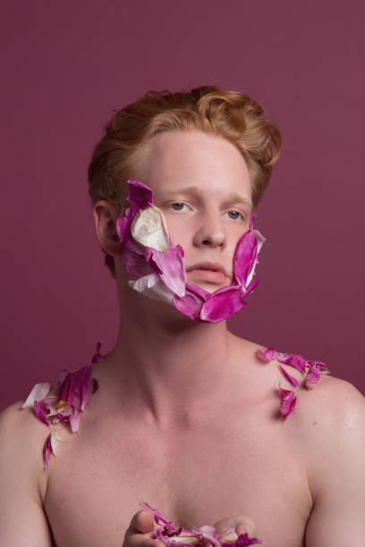 istock Young redhead man with flower petals on his face 1161799010