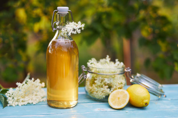 Bottle of elderflower syrup and elderberry flowers Bottle of elderflower syrup and elderberry flowers on wooden table elderberry photos stock pictures, royalty-free photos & images