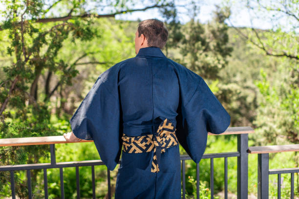 jeune homme dans le costume de kimono restant en arrière se penchant sur la barrière de balustrade dans le jardin extérieur au japon avec la vue de nature - obi sash photos et images de collection