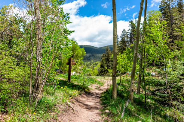 Santa Fe National Forest park trail with sign entrance at trailhead Sangre de Cristo mountains and green aspen trees by parking lot Santa Fe National Forest park trail with sign entrance at trailhead Sangre de Cristo mountains and green aspen trees by parking lot santa fe new mexico mountains stock pictures, royalty-free photos & images