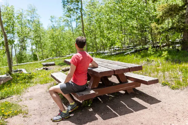 Santa Fe National Forest park Sangre de Cristo mountains with man sitting at picnic table green aspen trees in spring