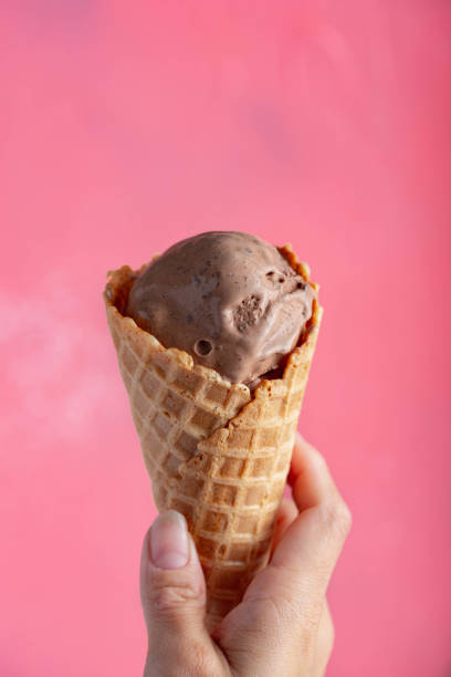 istock holding chocolate icecream in waffle cone on pink
 background 1161805861