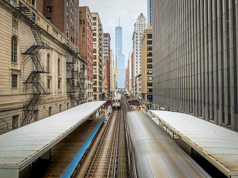 Aerial View of Two Trains Passing Each Other at a Train Stop in Chicago, Illinois - Surrounded by Buildings on Each Side, with Skyscrapers in the Background