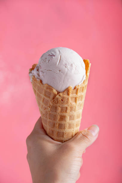 istock holding strawberry icecream in waffle cone on pink background 1161806384