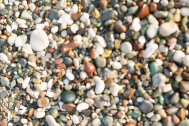 Blurred colorful small sea stone pebble background. Multicolored abstract beach nature pattern.