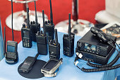 Many portable radio transceivers on table at technology exhibition. Different walkie-talkie radio set. Communication devices choice for military and civil use
