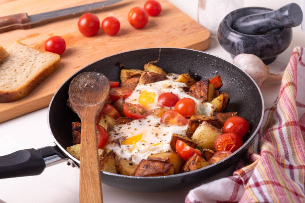 istock Men's rustic breakfast - fried potatoes with eggs and cherry tomatoes in a pan, standing on a wooden kitchen table. 1161811467