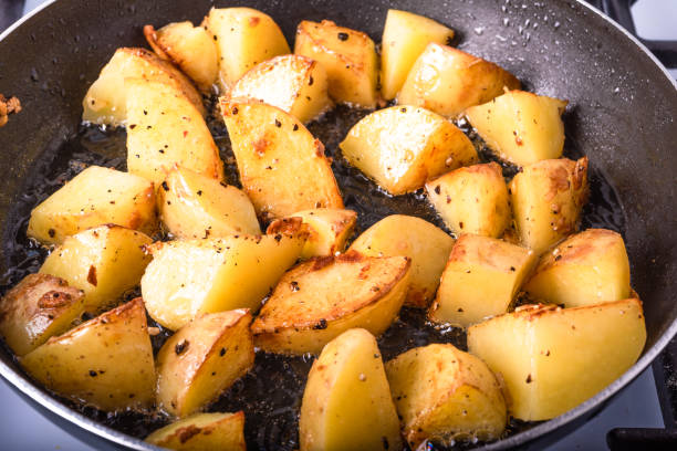 Cooking a rustic breakfast - large pieces of potatoes are fried in a pan Cooking a rustic breakfast - large pieces of potatoes are fried in a pan overcasting stock pictures, royalty-free photos & images