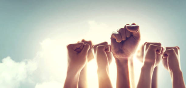 Peoples raised fist air fighting and sunlight effect, Competition, teamwork concept.