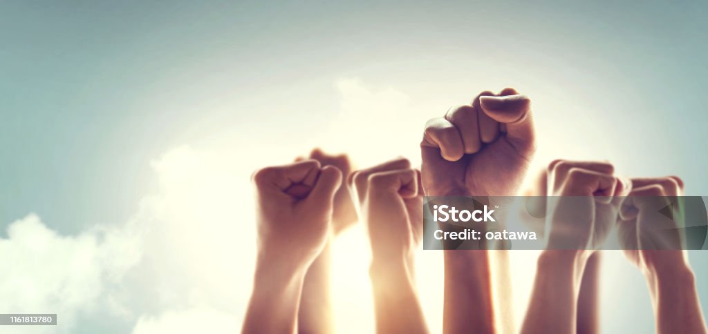 Peoples raised fist air fighting and sunlight effect, Competition, teamwork concept. Strength Stock Photo