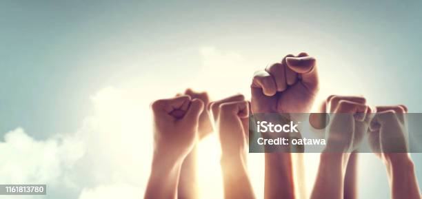 Peoples Raised Fist Air Fighting And Sunlight Effect Competition Teamwork Concept Stock Photo - Download Image Now