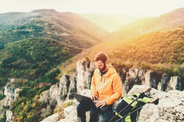Hiker resting on the mountain top and using tablet