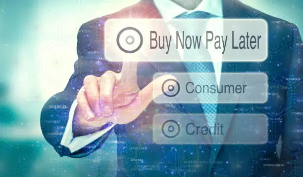 A businessman selecting a button on a futuristic display with a Buy Now Pay Later concept written on it.