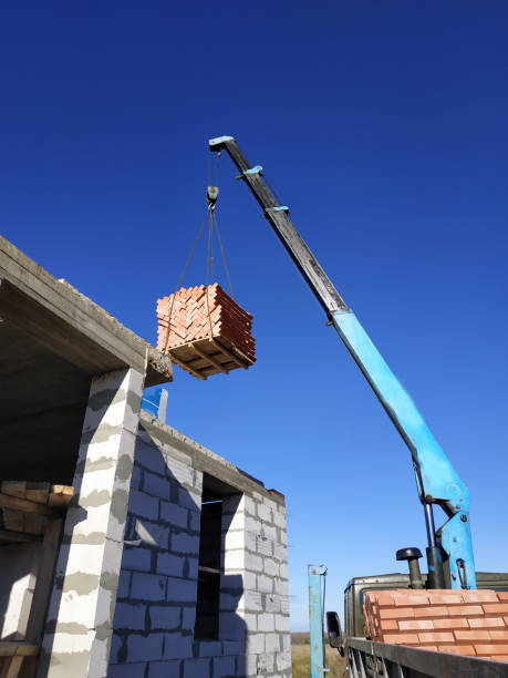 istock The crane raises a brick on the back of a blue sky 1161815528