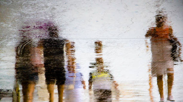 istock Blurry reflection silhouette  in a puddle of people walking on a rainy day 1161819482