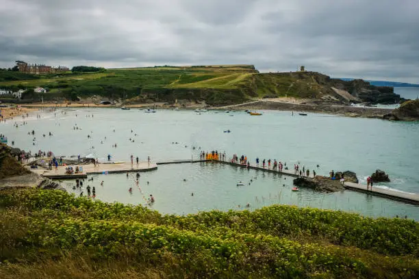 People having a summer beach holiday at the sea pool, a partially man-made tidal swimming pool at Summerleaze Beach.