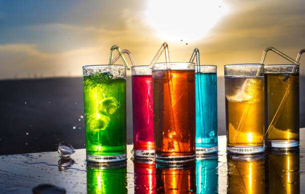 Cooling summer drink concept. Cocktail glasses splashing on sunset. Close up wet glass of cold drink on the terrace.