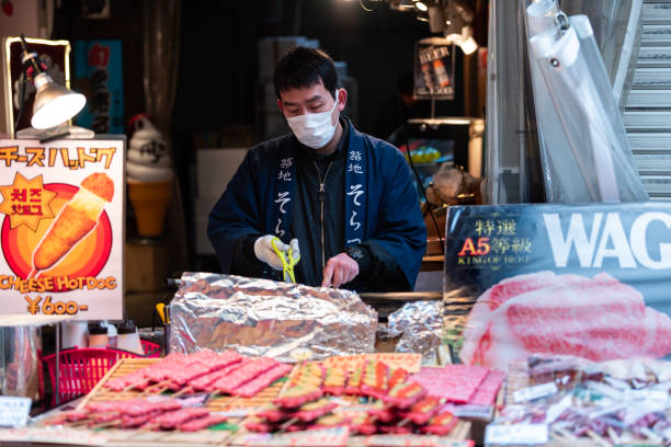 manzo wagyu infilzato, caviale riccio di mare su spiedini nel mercato ittico esterno di ginza con l'uomo venditore che cucina carne alla griglia - 11088 foto e immagini stock