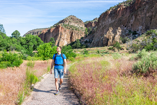 Main Loop path trail with man walking in Bandelier National Monument in New Mexico in Los Alamos with canyon cliffs