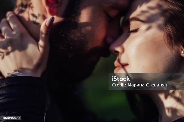 Head Shot Of Young Affectionate Romantic Couple In Love Close Up Portrait Of Attractive Brunette Girl And Guy With Eyes Closed Close To Each Other Concept Of First Kiss Tenderness And Amorousness Art Shadow On The Face Stock Photo - Download Image Now
